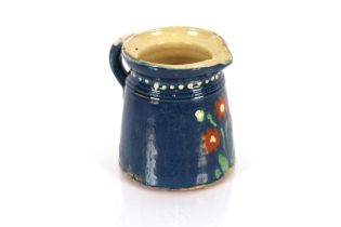 A glazed earthenware jug, with floral and white dot decoration on a blue and cream ground 25cm