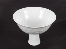 A Chinese white porcelain stem bowl, with finely moulded decoration of clouds and dragons, marked to