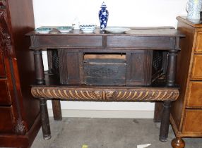 An early oak two tier buffet, the upper section fitted with a cupboard enclosed by a gouged panelled