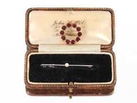 A yellow metal and garnet circular brooch and a 9ct white gold and pearl set bar brooch (2)