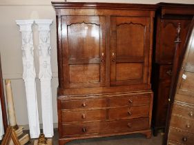 An antique oak press cupboard, the hanging compartment enclosed by a pair of panelled doors above