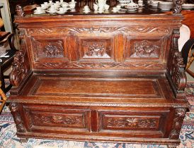 A 19th Century carved oak hall settle, decorated with panels of figures within trailing foliate