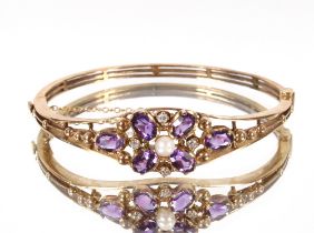 A 9ct gold diamond and amethyst set bangle, the central pearl surrounded by an arrangement for