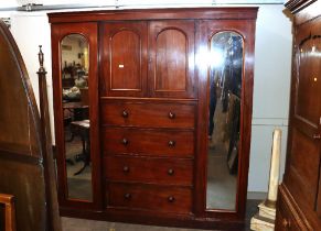 A Victorian mahogany combination wardrobe, fitted central shelves enclosed by arched panel doors,