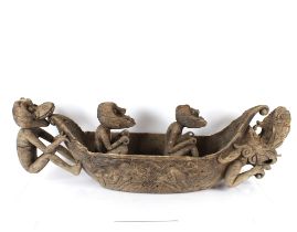 An unusual Ethnic carved softwood model of a dugout canoe with seated grotesque figures and beast