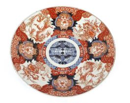 A large Japanese Imari charger decorated in the traditional palette with figures, dragons and