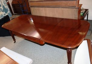 A mahogany extending dining table fitted with two extra leaves raised on reeded tapering supports,