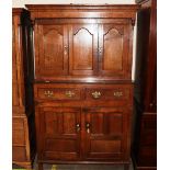 An antique oak livery cupboard, the upper section surmounted by a stepped canopy above cupboards,