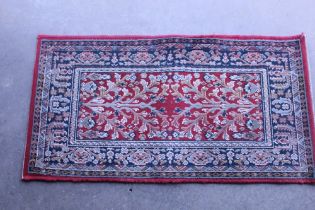 An approx. 3'8" x 1'11" red patterned rug