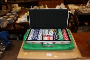 A cased set of poker chips and a roulette wheel