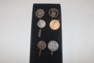 A collection of stick pins decorated with coins