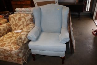 A blue upholstered wing back arm chair