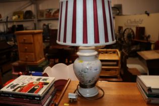 A floral decorated table lamp with striped shade