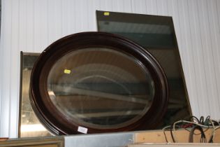 An oval framed bevel edged wall mirror together wi