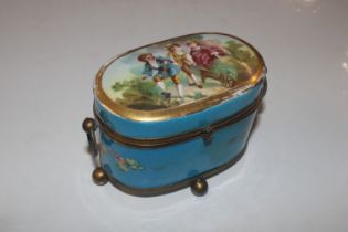 A metal and porcelain trinket box flanked by ring