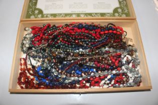 A wooden box and contents of bead necklaces