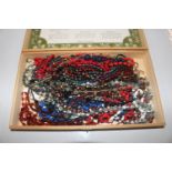 A wooden box and contents of bead necklaces