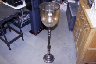 A floor standing metal and glass candle stand