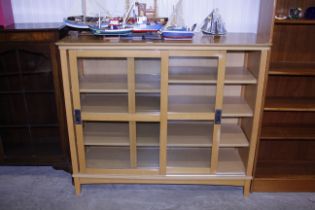 A light oak display cabinet enclosed by glazed sli