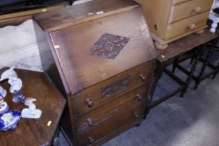 An oak bureau with carved decoration fitted three