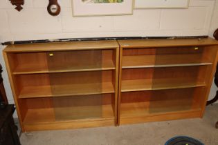 A pair of three tier bookcases enclosed by glass s