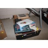 A box containing books, tins, flags, lamp shade et