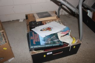 A box containing books, tins, flags, lamp shade et