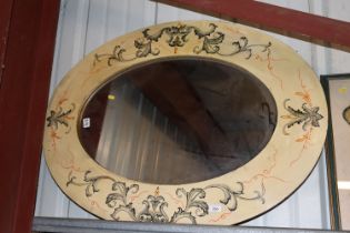 A painted and decorated oval framed mirror