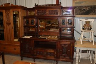 A late 19th Century Gillows style oak mirrored back sideboard having carved panels and stained glass