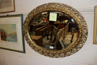 A gilt framed oval bevel edge wall mirror