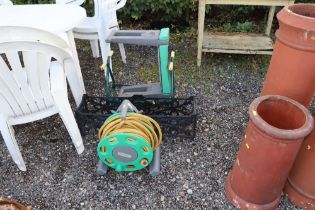 A garden hose and reel, a planter and two garden k