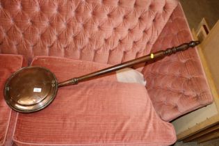 A copper warming pan on turned wooden handle