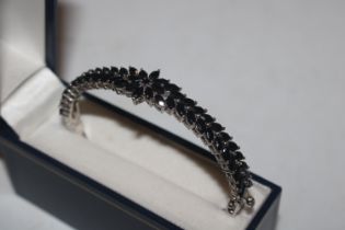 A silver hinged bangle set with black stones