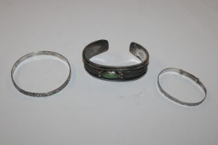 A silver bangle and two white metal bangles