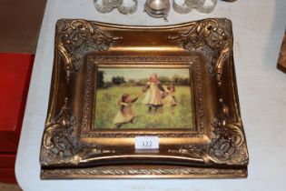 A gilt framed oleograph depicting children playing