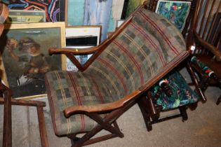 An early 20th Century upholstered armchair raised on X frame supports