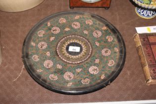 A circular papier mâché tray with floral decoratio