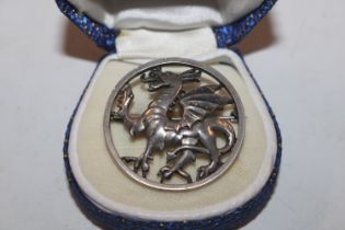 A circular silver brooch decorated with a dragon