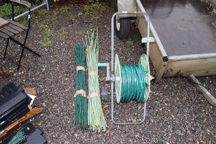 A garden hose and reel; a quantity of garden canes