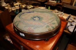 A circular footstool with embroidered upholstery