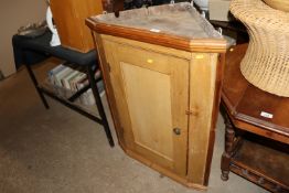 An antique stripped pine corner cupboard