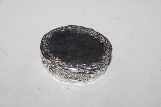 An oval silver pill box with embossed floral decor