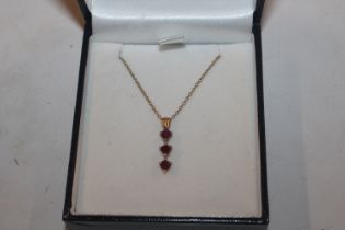 A yellow metal pendant marked 10K, set with ruby c