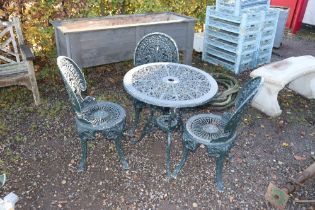 An ornate metal garden table and three chairs