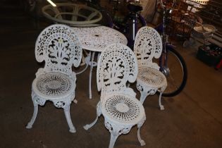 An ornate white painted garden table and three cha