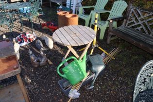 A wooden folding garden table; a tripod stand; two