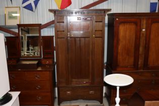 An oak Arts and Crafts type single door wardrobe fitted single drawer below, cornice decorated