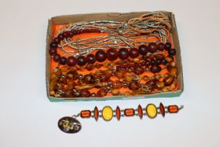 A tray of amber coloured and other necklaces