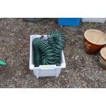 A plastic crate containing a hose pipe