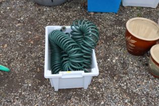 A plastic crate containing a hose pipe